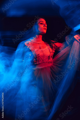 blurry abstract portrait of a young dancing girl in a dress on a black background © alexkoral