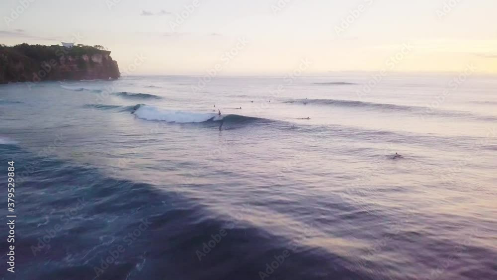 Bay with surfers in water riding waves with golden sunset on horizon, aerial Bay with surfers in water riding waves with golden sunset on horizon, aerial