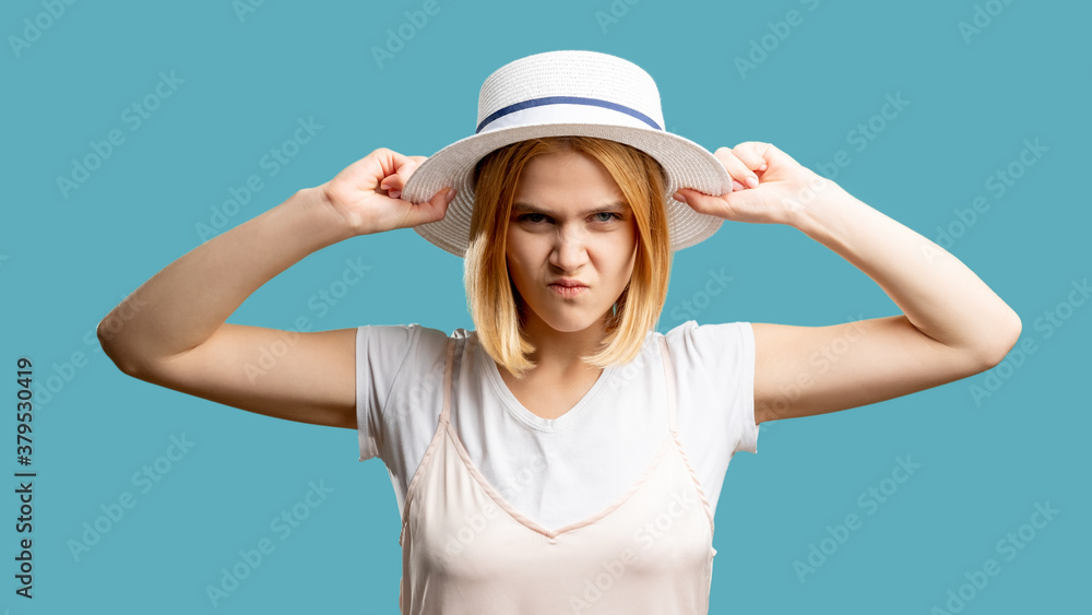 Angry woman. Travel ban. Mad lady in white summer outfit and hat looking at camera isolated on blue. Canceled vacation. Bad service. Overwhelmed hate. Negative emotion Angry woman. Travel ban. Mad lady in white summer outfit and hat looking at camera isolated on blue. Canceled vacation. Bad service. Overwhelmed hate. Negative emotion