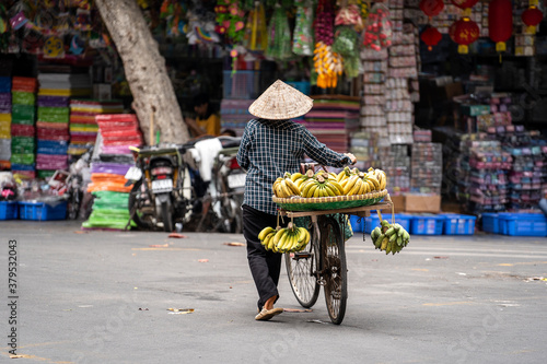 Vietnamese woman with bike selling bananas on the street market of old town in Hanoi, Vietnam