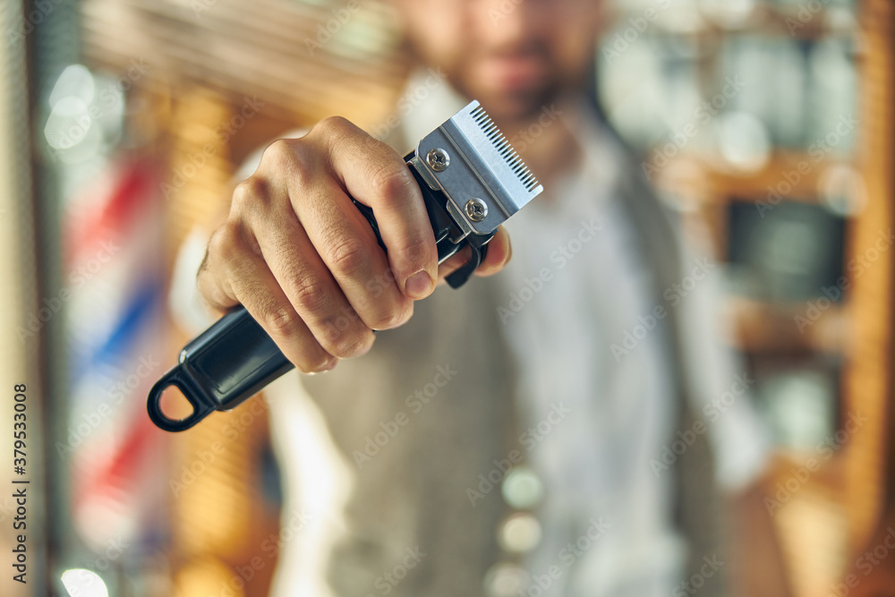 Photo of electric hair clipper in hands of a hair-stylist Photo of electric hair clipper in hands of a hair-stylist