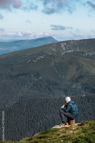 man sitting on the stump eating hiking food looking on mountains