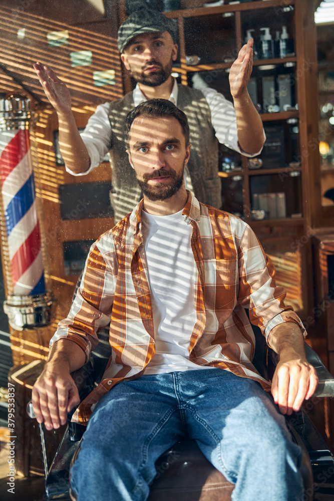 Stylish barber and hipster client posing at a barbershop