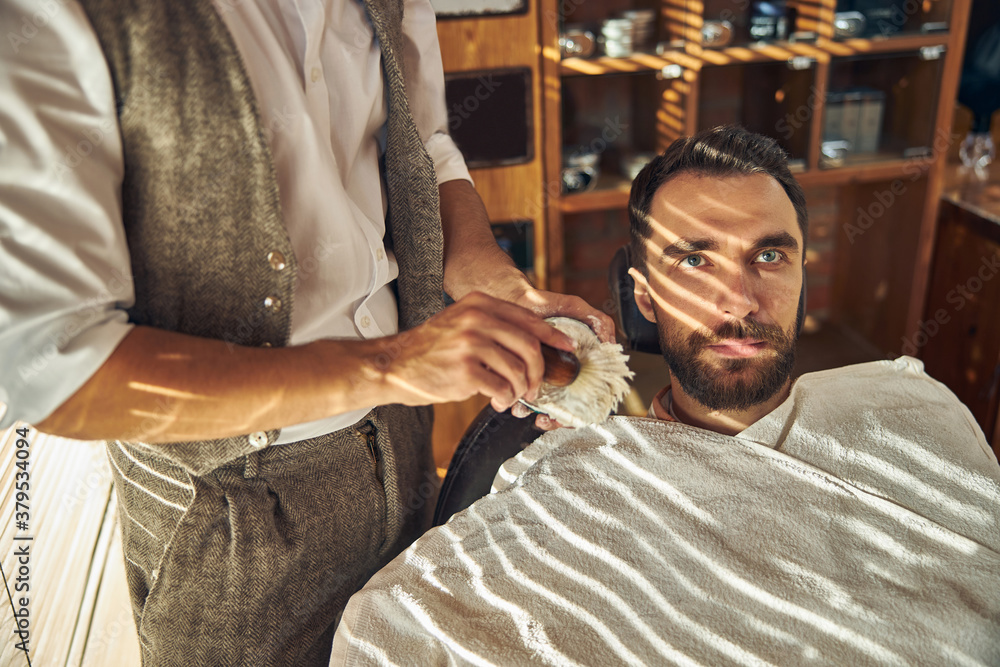 Bearded young man getting a fresh shave at barbershop