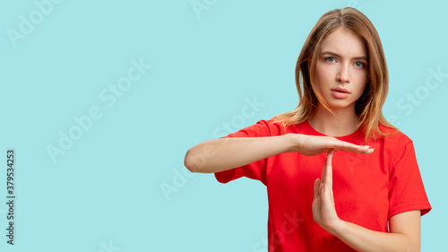 Time up. Break gesture. Portrait of confident protesting woman in red t-shirt showing T sign with hands isolated on blue copy space background. Restriction rejection. Pause signal. photo