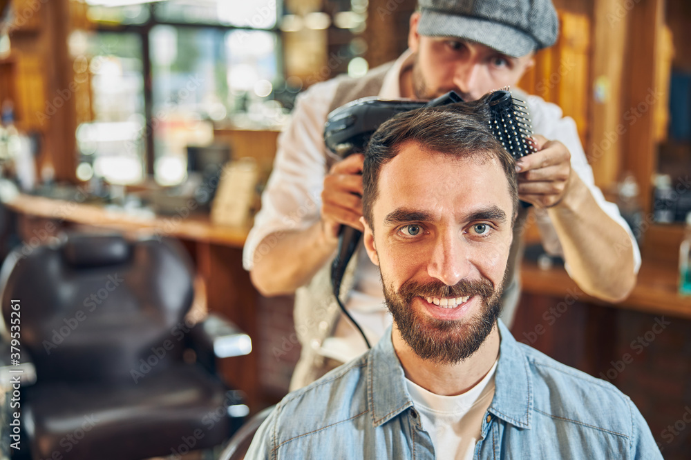 Obraz premium Young brunette man having an appointment at barbershop