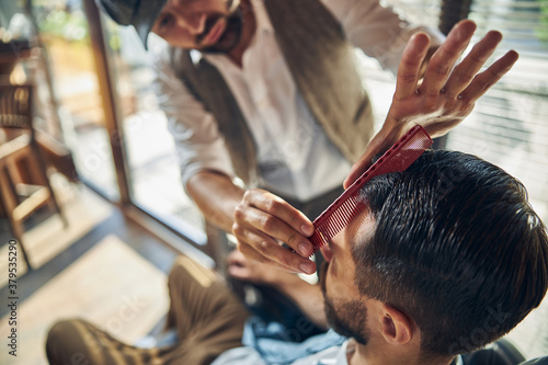 Enthusiastic hair-stylist working on a new look of his customer