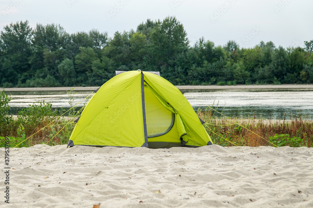       Yellow tent on the sandy bank of the river.