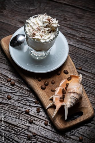 Ice Cream with vanilla coffee, Affogato al Caffe. Coffee Frappe Galao macchiato with shell on the dark old wooden table. Coffee beans. Glass on the white plate. Irish coffee, cafe au lait, cortado