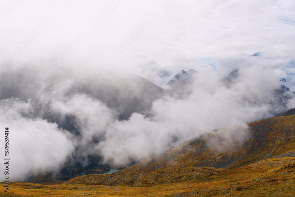 Alpine landscape. Photo of clouds from a high mountain. The birth of clouds in the mountains. Soft focus. Clouds float between the mountains.