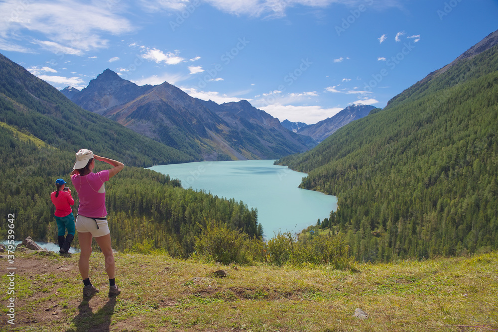 Women admire the beautiful mountain lake. Tourists, mountains, lake, travel.