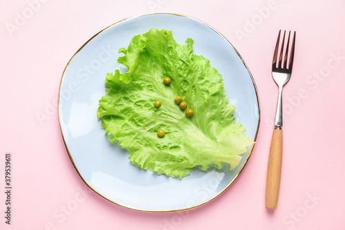 Plate with vegetables and fork on color background. Concept of anorexia