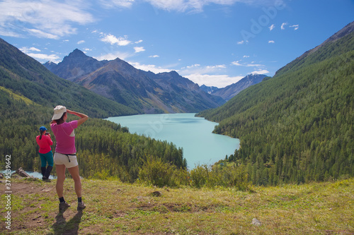 Women admire the beautiful mountain lake. Tourists, mountains, lake, travel. © Sergei