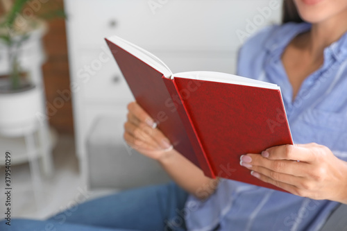 Beautiful young woman reading book at home, closeup