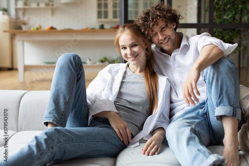 Young couple sitting on sofa looking at camera. Enjoy together.