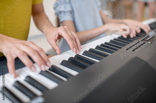 Close up picture of two people playing piano together