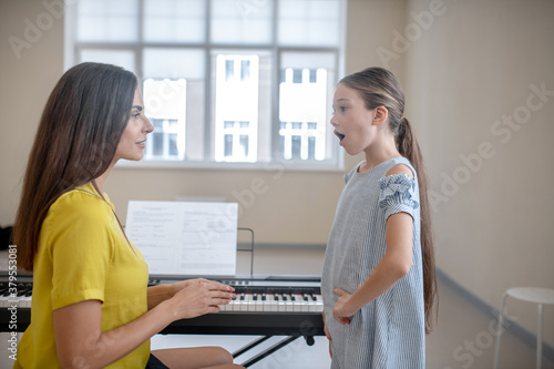 Girl in a blue dress having a vocal lesson photo