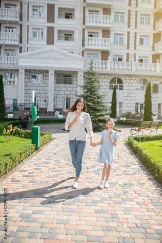 Mom and daughter walking together and eating ice-cream © zinkevych