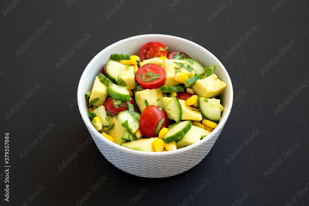 Fresh Avocado Tomato Salad in a bowl on a black background, side view. Fresh Avocado Tomato Salad in a bowl on a black background, side view.