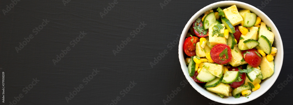 Fresh Avocado Tomato Salad in a bowl on a black surface, top view. Flat lay, overhead, from above. Copy space. Fresh Avocado Tomato Salad in a bowl on a black surface, top view. Flat lay, overhead, from above. Copy space.