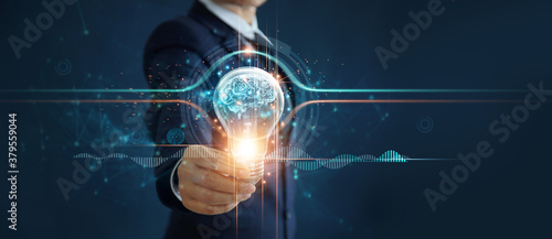 Businessman holding illuminated light bulb with brain inside, idea, creativity, innovation and inspiration of business on network connection background.