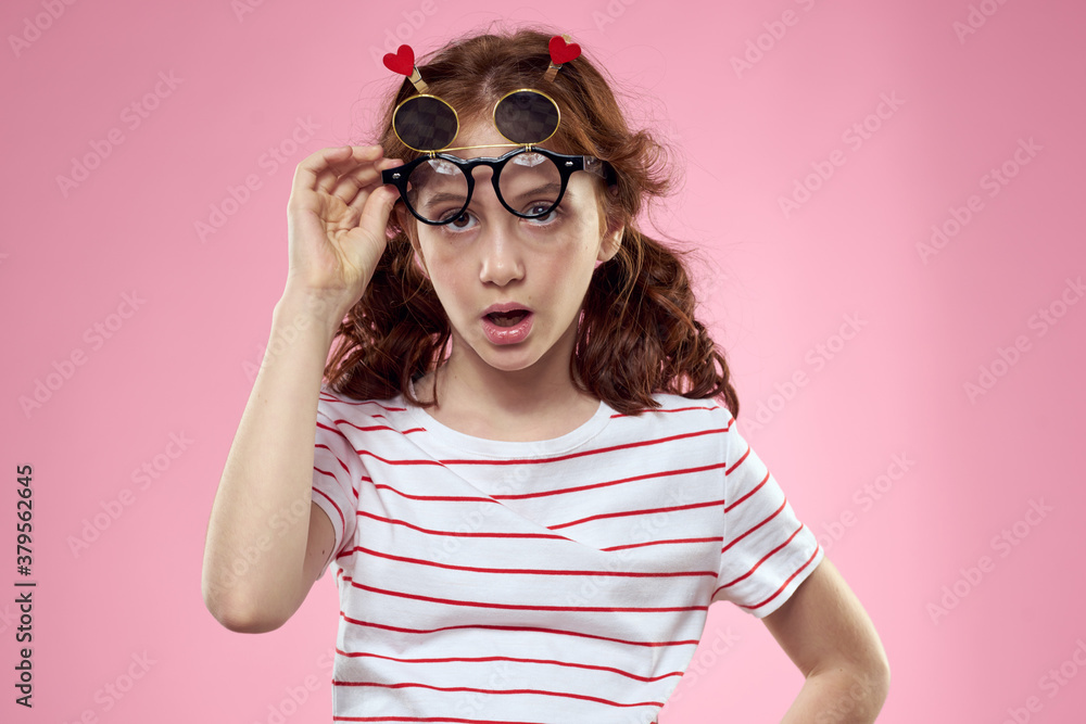Cute girl sunglasses striped t-shirt lifestyle fun style pink background Cute girl sunglasses striped t-shirt lifestyle fun style pink background