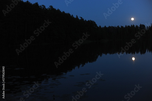 Mysterious and magic glowing full moon reflecting in a lake during night in Poland in Europe