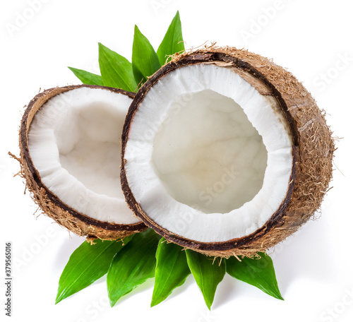 Split coconut fruit with white flesh over green leaves isolated on white background.