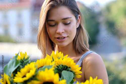 woman is walking in the old town. He is holding a bouquet of autumn sunflowers in his hand photo