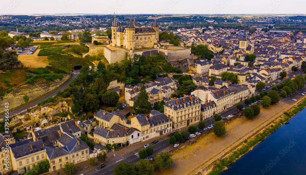 Drone view of ancient Chateau de Saumur and church of St. Peter with cityscape on background on sunny summer day, France