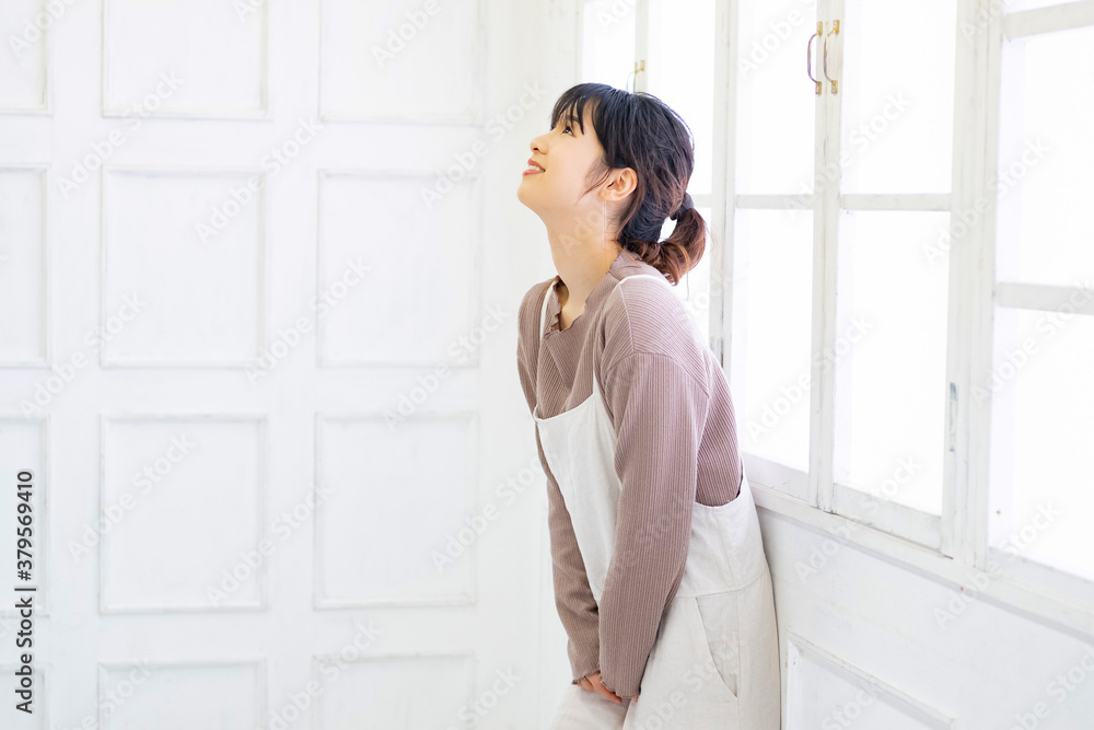 部屋の窓際に立つ若い女性 部屋の窓際に立つ若い女性