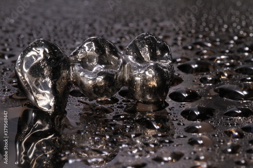 Closeup of silver/metal cast molars-crowns on black background