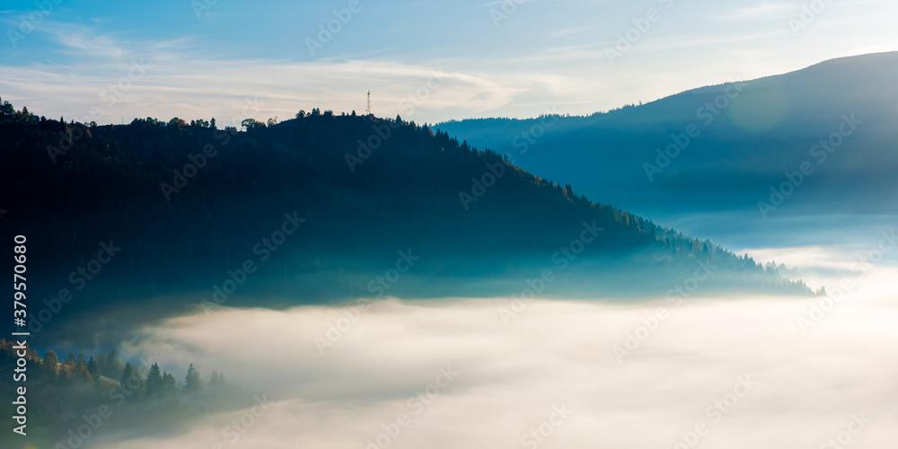idyllic autumn landscape with cold morning fog on hillside in mountainous rural area at sunrise