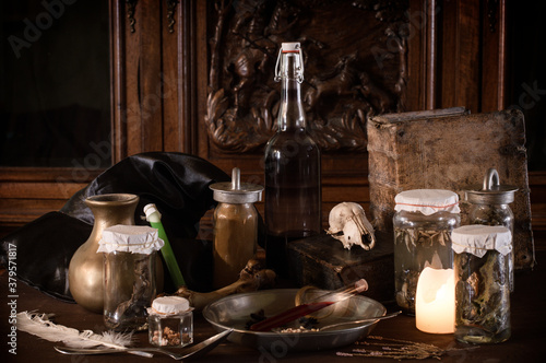 eerie witches' kitchen with lot of ingredients for a potion and ancient gruesome jars dark with only candlelight for Halloween