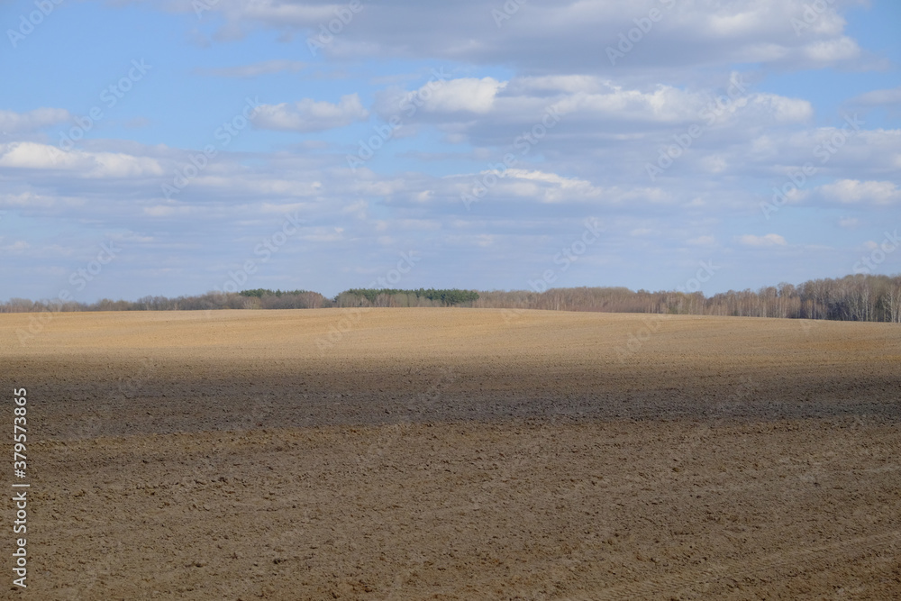 A plowed agricultural field. Blue sky over a farm field. A plowed agricultural field. Blue sky over a farm field.