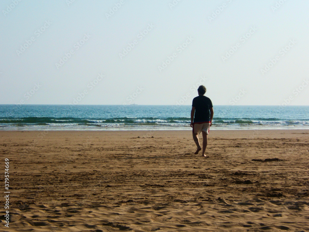 a man walks towards the sea on Agadir beach, Morocco