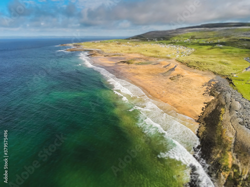 Aerial drone view on Fanore beach, county Clare, Ireland. Warm sunny day, People on the beach and surfing in the water. Cloudy sky, Popular surfing spot.