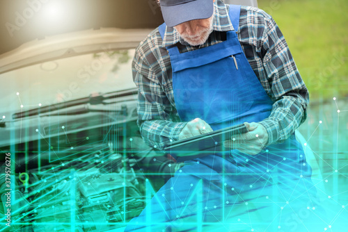 Mechanic using digital tablet for checking car engine; multiple exposure