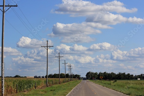 power lines in the countryside with a blue sky,clouds, and a highway north of Hutchinson Kansas USA out in the country.