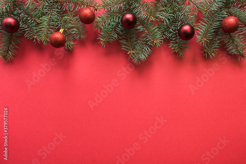 Christmas banner with fir branches, red balls on red background. View from above with copy space, flat lay. Xmas greeting card. Happy New Year. photo