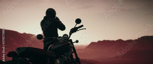 Biker enjoying a scenic view of a sunset over mountains during motorcycle ride photo