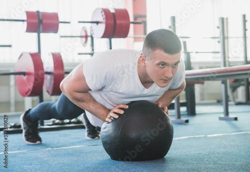 athlete push ups on a black ball in the gym