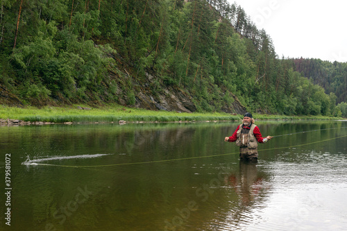 Fly fishing. Fisherman alone stand in river water. Hobby sport activity