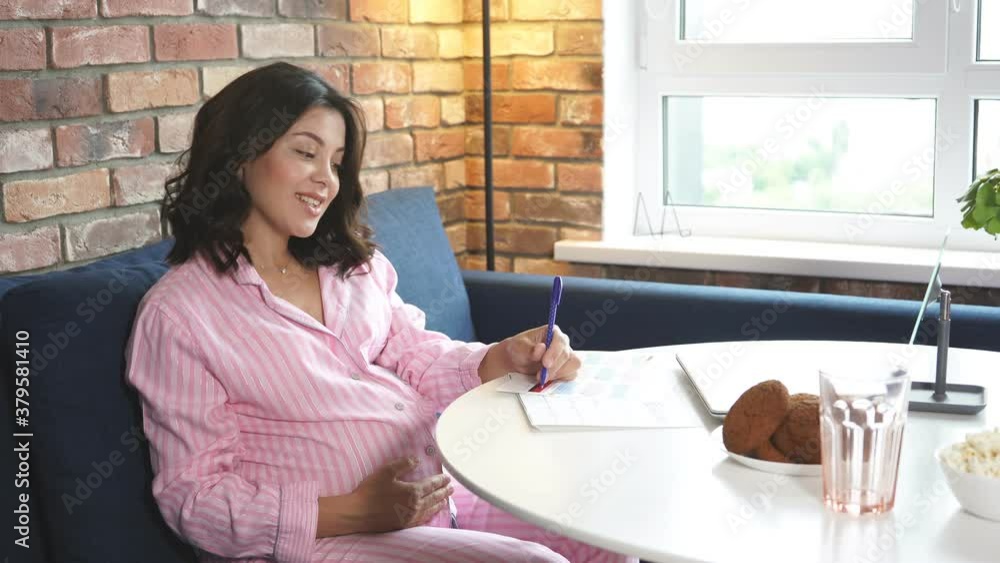 Happy pregnant woman writing in her pregnancy calendar, at home. Keeping a journal, expecting baby. Happy pregnant woman writing in her pregnancy calendar, at home. Keeping a journal, expecting baby.