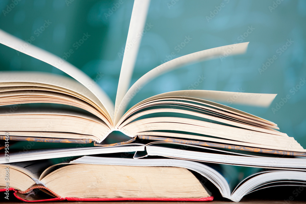 A stack of books opened in front of the blackboard A stack of books opened in front of the blackboard