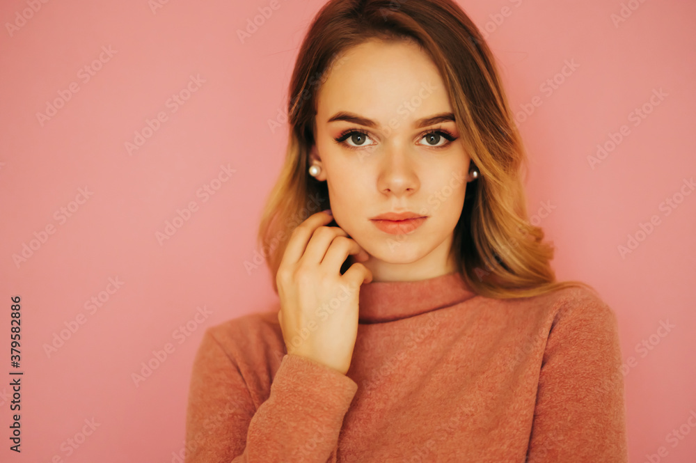 Closeup portrait beautiful young woman standing on a pink background and posing for the camera. Closeup portrait beautiful young woman standing on a pink background and posing for the camera.
