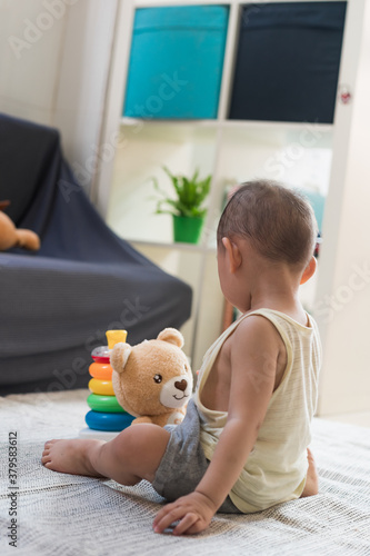 A 1.5-year-old baby boy plays with educational toys on the carpet