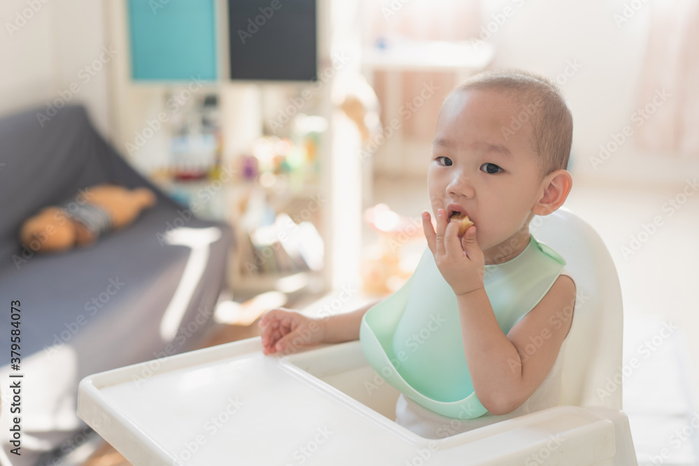 A one-and-a-half-year-old boy eats in a dining chair A one-and-a-half-year-old boy eats in a dining chair