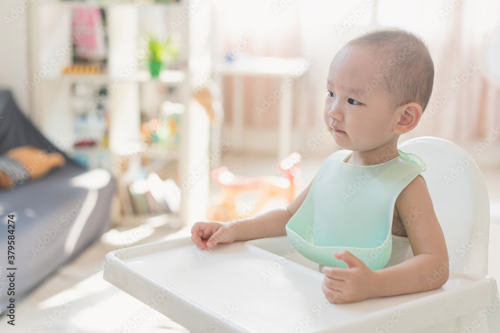 A one-and-a-half-year-old boy eats in a dining chair A one-and-a-half-year-old boy eats in a dining chair