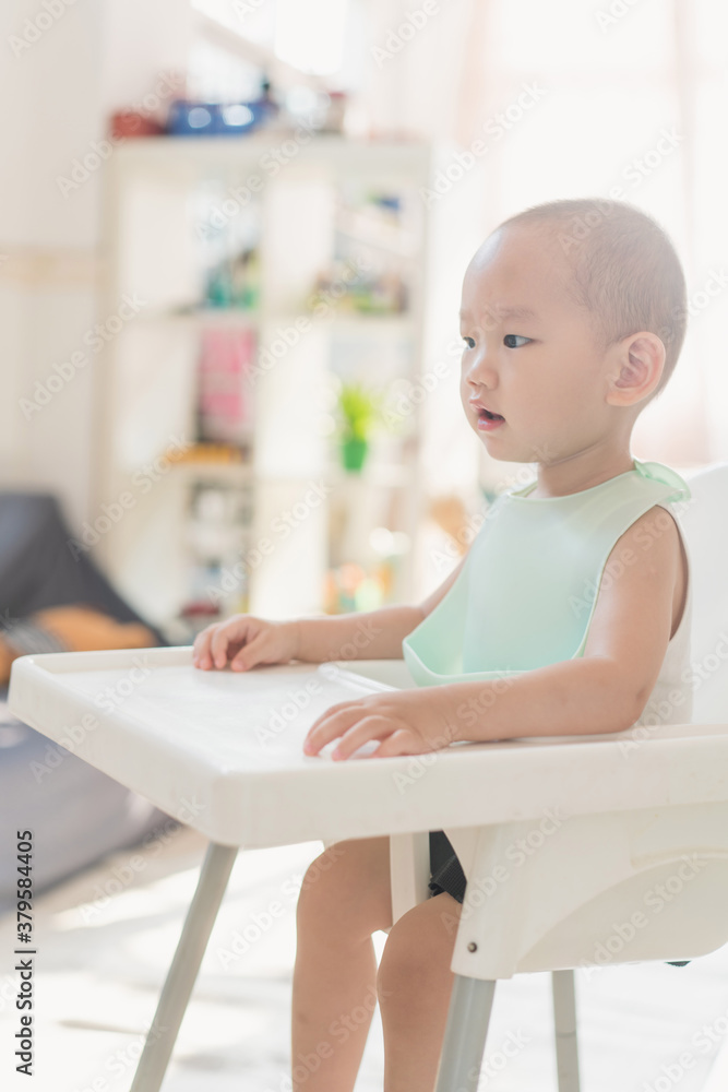 A one-and-a-half-year-old boy eats in a dining chair A one-and-a-half-year-old boy eats in a dining chair